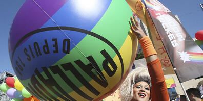 Die Teilnehmer gehen während einer Pride Parade durch eine Straße. Foto: Chiang Ying-Ying/AP/dpa