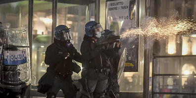 Polizisten setzen während eines Protests gegen die Corona-Maßnahmen der Regierung in Turin Tränengas ein. Foto: Claudio Furlan/LaPresse/AP/dpa