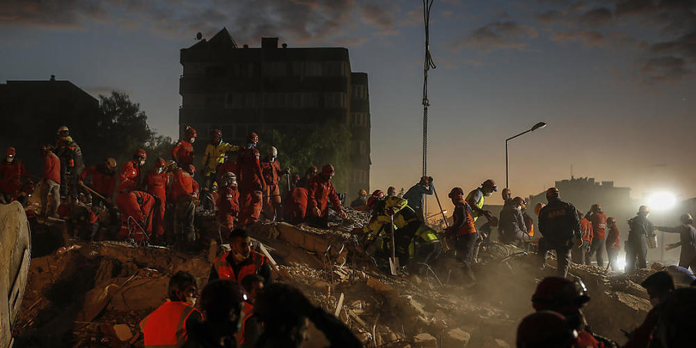 Mitglieder des Rettungsdienstes suchen in den Trümmern eines eingestürzten Gebäudes in Izmir nach Überlebenden. Foto: Darko Bandic/AP/dpa