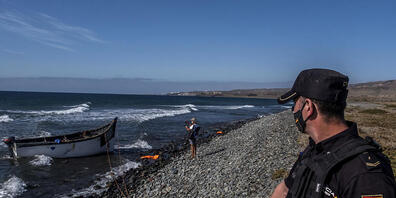 ARCHIV - Ein spanischer Polizist sichert ein Holzboot, mit dem Flüchtlinge aus Marokko nach der Fahrt über den Atlantischen Ozean auf den Kanarischen Inseln angekommen sind. Foto: Javier Bauluz/AP/dpa