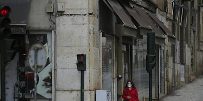 ARCHIV - Eine Frau mit Maske geht eine sehr ruhige Straße in der Innenstadt entlang. Foto: Armando Franca/AP/dpa