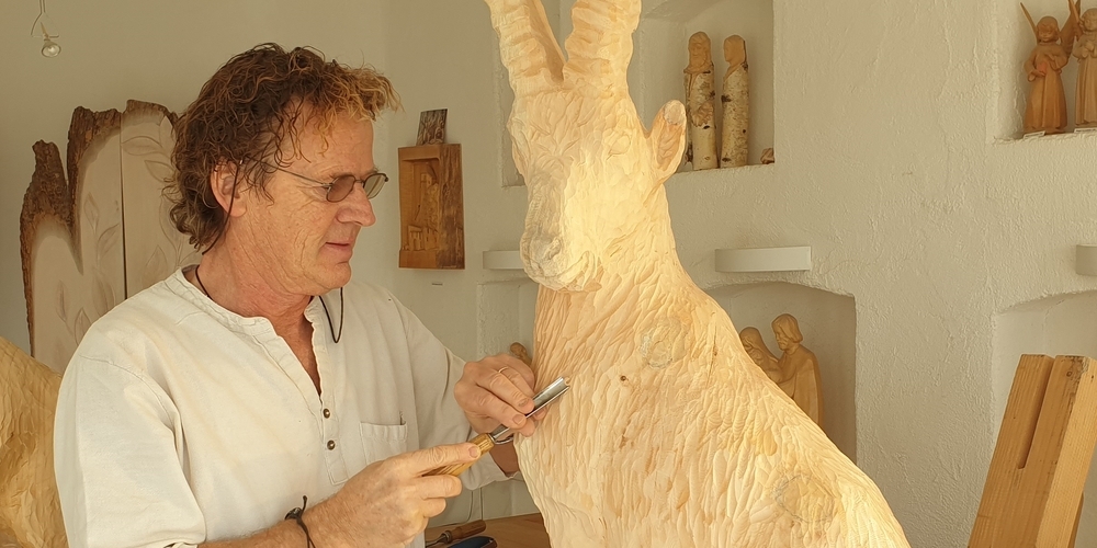 Paul Widmer schnitzt ein Kunstwerk aus Arvenholz. Der Steinbock ist das meist gewünschte und beliebteste Motiv des Künstlers.