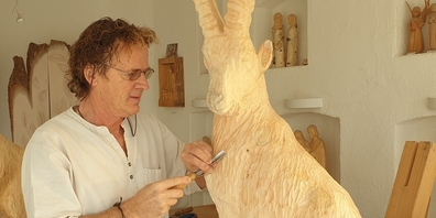 Paul Widmer schnitzt ein Kunstwerk aus Arvenholz. Der Steinbock ist das meist gewünschte und beliebteste Motiv des Künstlers.
