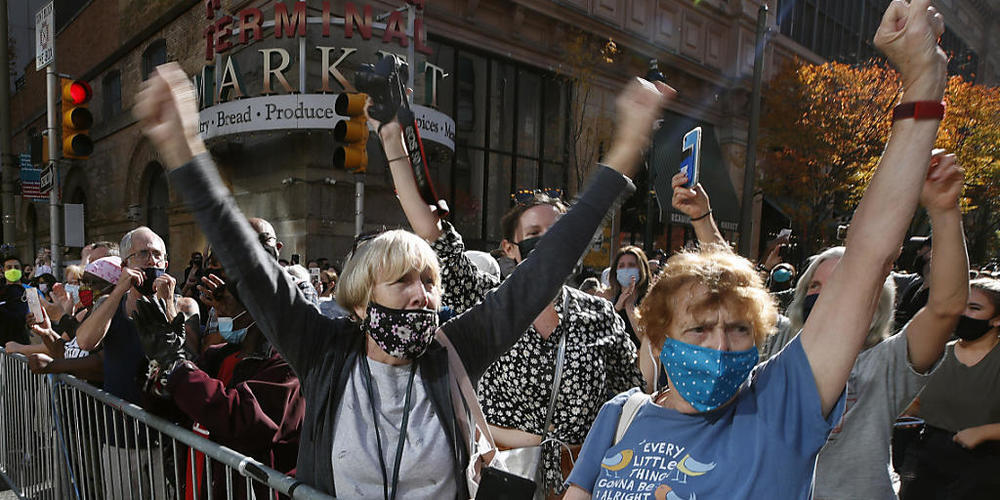 Menschen mit Mund-Nasen-Schutz feiern vor dem Pennsylvania Convention Center, nachdem der demokratische Präsidentschaftskandidat Joe Biden zum Sieger erklärt wurde. Foto: Rebecca Blackwell/AP/dpa