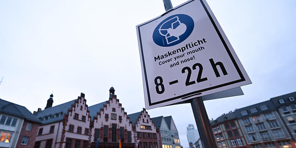 Ein Schild mit der Aufschrift "Maskenpflicht. Cover your mouth and nose! 8 - 22 h" ist auf dem Römerberg an einem Laternenpfahl befestigt. Nach der Video-Konferenz mit der Kanzlerin hat Hessens Landesregierung hat noch keine Entscheidung über mögl...