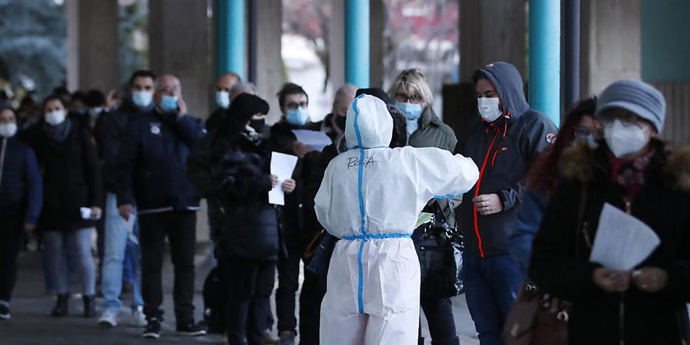 Menschen stehen vor einer Corona-Schnelltest-Einrichtung in Bozen Schlange. Foto: Antonio Calanni/AP/dpa