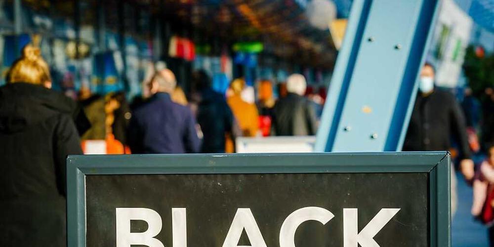 Passanten gehen vor einem Einkaufszentrum an einem Schild vorbei, das auf «Black Friday»-Angebote hinweist. Menschenmassen in Einkaufsstraßen und drohende Verstöße gegen Corona-Regeln: In den Niederlanden lehnen sich Städte gegen die Verkaufsaktio...
