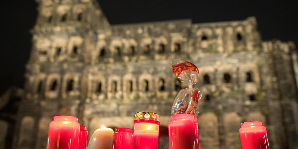 Vor der Porta Nigra brennen Kerzen. Am Nachmittag war ein Mann mit einem Auto durch die Fußgängerzone von Trier gefahren und hat dabei Menschen verletzt und getötet. Foto: Oliver Dietze/dpa