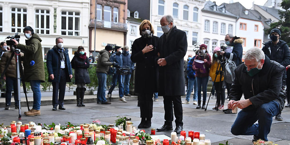 Malu Dreyer (SPD), Ministerpräsidentin von Rheinland-Pfalz, und ihr Ehemann Klaus Jensen stehen vor Blumen und Kerzen, die vor der Porta Nigra im Gedenken der Opfer der Amokfahrt eines 51-jährigen Mannes durch die Innenstadt niedergelegt wurden. F...
