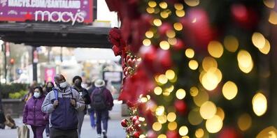 Menschen mit Mund-Nasen-Schutz gehen an Geschäften mit weihnachtlicher Dekoration vorbei. Foto: Wang Ying/XinHua/dpa