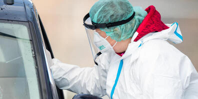Eine Mitarbeiterin macht in einem Corona-Abstrich-Zentrum bei einem Autofahrer einen Abstrich für einen Corona-Test. Foto: Tom Weller/dpa