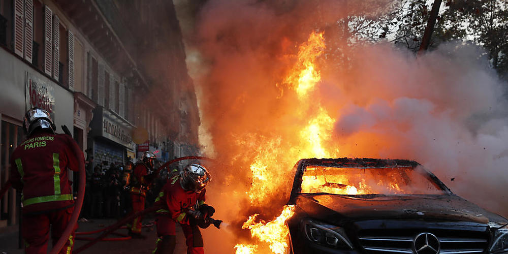 Die Feuerwehr löscht ein brennendes Auto in Paris. Foto: Francois Mori/AP/dpa