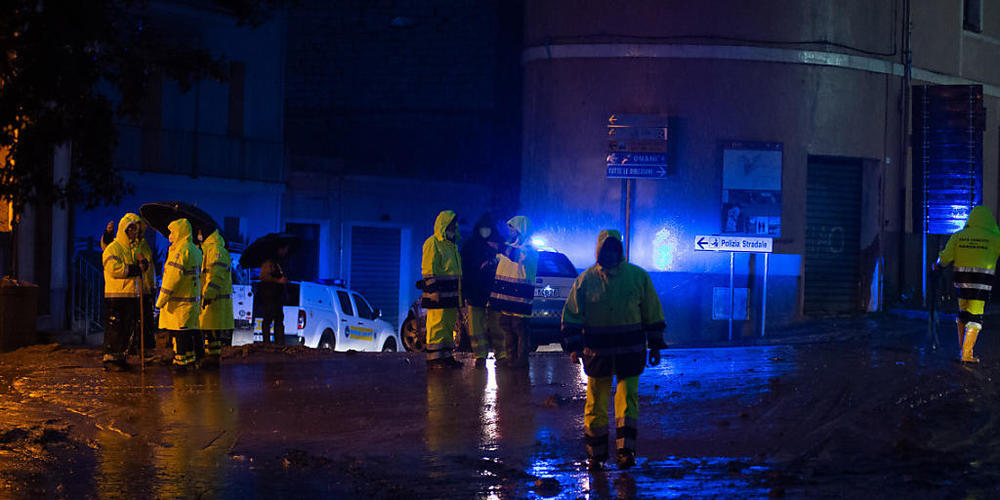 Rettungskräfte stehen an einer mit Schlamm überzogenen Straße. Foto: Alessandro Tocco/LaPresse via ZUMA Press/dpa