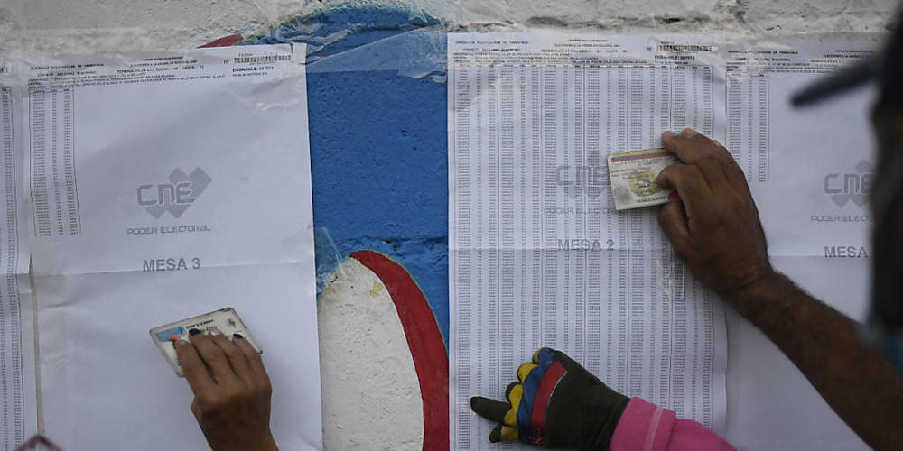 Einwohner von Caracas überprüfen auf einem Aushang, in welchem Wahllokal sie ihre Stimme abgeben müssen. Foto: Matias Delacroix/AP/dpa