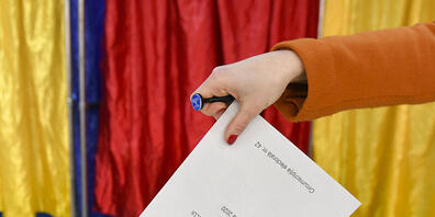 Eine Frau gibt ihren Stimmzettel ab. Foto: Andreea Alexandru/AP/dpa