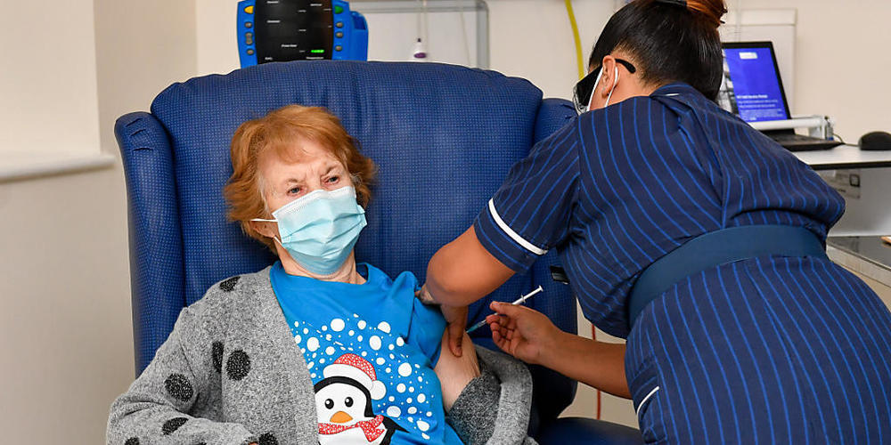 Die 90-jährige Margaret Keenan (l) bekommt im Universitätskrankenhaus Coventry von der Krankenschwester May Parsons den Pfizer/BioNtech-Impfstoff gegen das neuartige Coronavirus. Foto: Jacob King/PA Wire/dpa