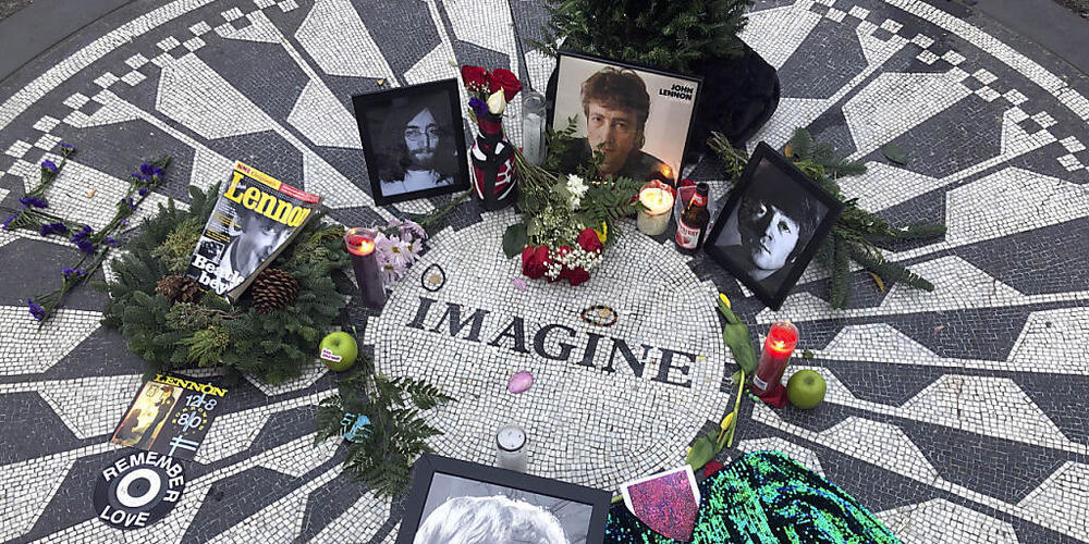Fotos, Blumen und Kerzen stehen auf der Gedenkstätte Strawberry Fields im Central Park zur Erinnerung an John Lennon. Vor genau 40 Jahren wurde der Beatles-Musiker in New York erschossen. Der Mörder sitzt bis heute im Gefängnis. Foto: Mark Lenniha...