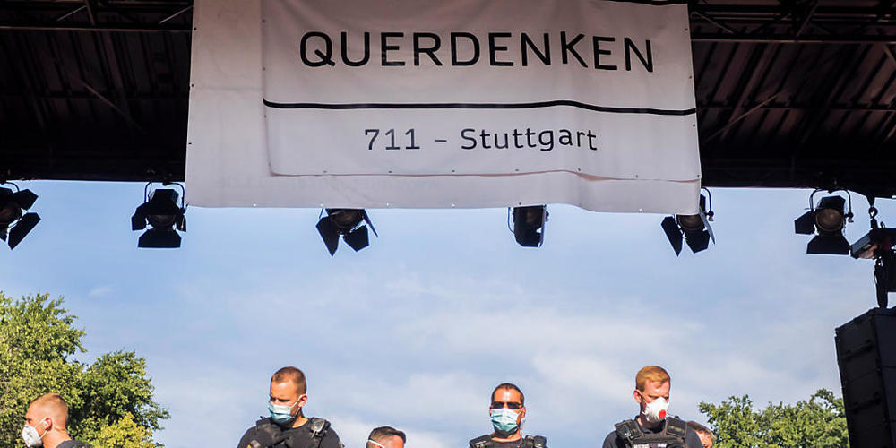 ARCHIV - Polizisten stehen bei einer Kundgebung gegen die Corona-Beschränkungen auf der Straße des 17. Juni auf der Bühne unter dem Banner der Initiative «Querdenken 711». Die Polizei hatte die Veranstaltung aufgelöst. Foto: Christoph Soeder/dpa