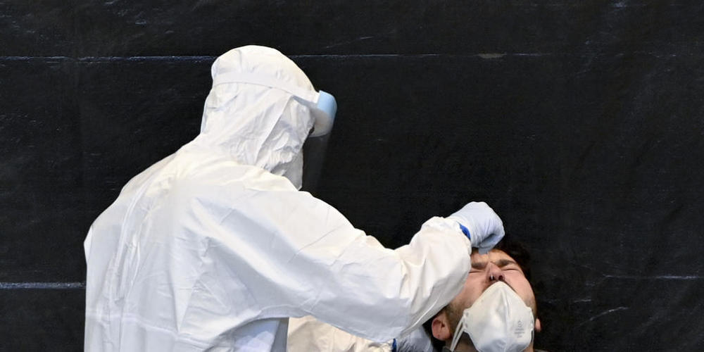 Ein Mitarbeiter in Schutzkleidung führt bei einem Mann einen Abstrich für einen Corona-Test durch. Foto: Herbert Neubauer/APA/dpa