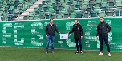 Ralf Zeller und Joah Lenzo, Mitarbeitende der A. Lehmann AG, überreichten den Scheck an en FCSG-Präsidenten Matthias Hüppi.