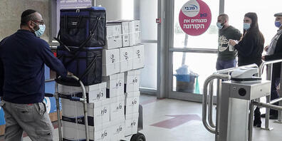 Eine Person mit Mund-Nasen-Schutz bringt Kartons mit dem Corona-Impfstoff von Pfizer-Biontech in die Pais Arena. Foto: Nir Alon/ZUMA Wire/dpa