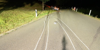 Verunfallter Personenwagen im Wiesland sowie mit Kreide markierte Reifenspuren im Vordergrund.