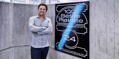 Philip Kerschbaum vor dem Ankündigungsplakat, welches immer im Jahrgangsdesign gestaltet ist.