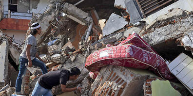 Anwohner inspizieren ein Gebäude, das bei einem Erdbeben eingestürzt ist. Foto: Yusuf Wahil/AP/dpa
