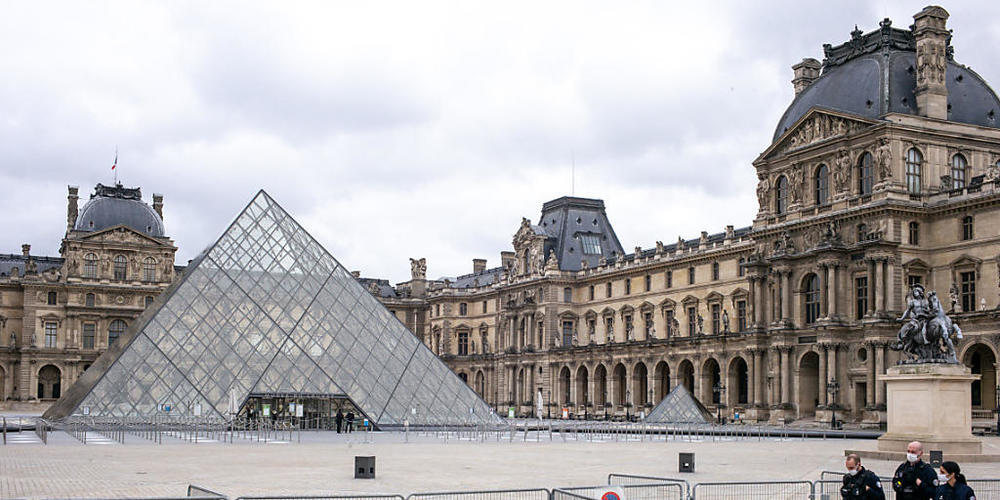 ARCHIV - Der Louvre ist geschlossen, der Platz davor ist leer. Nur drei Polizisten gehen an einer Absperrung entlang. Foto: Elko Hirsch/dpa