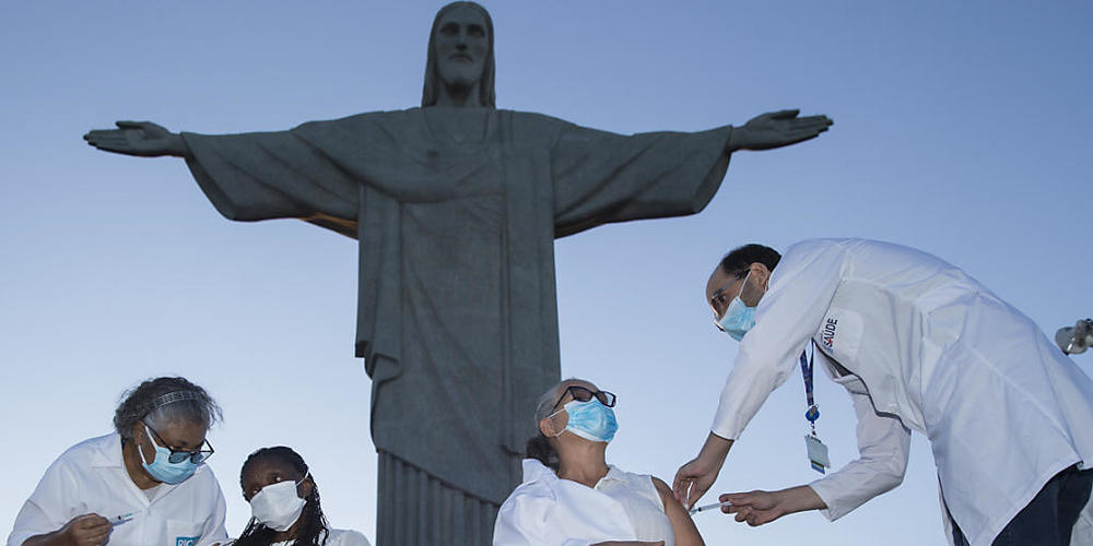 dpatopbilder - Zwei Frauen erhalten bei einm Impftermin vor der Christus-Statue eine Covid-19-Impfung. Foto: Fernando Souza/dpa