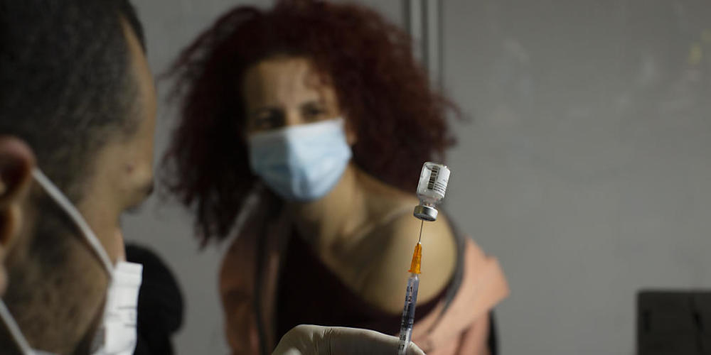Eine medizinische Fachkraft bereitet sich darauf vor, einer Frau in einem Impfzentrum in einer Sportarena in Jerusalem den Impfstoff gegen Covid-19 von Pfizer-Biontech zu verabreichen. Foto: Maya Alleruzzo/AP/dpa