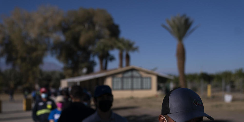 Eingewanderte Landarbeiter tragen Mund-Nasen-Bedeckungen und warten in einer Schlange, um die Corona-Impfung zu erhalten. Verbände warnen davor, dass Millionen Einwanderer zu den am schwierigsten zu erreichenden Menschen während der größten Impfka...