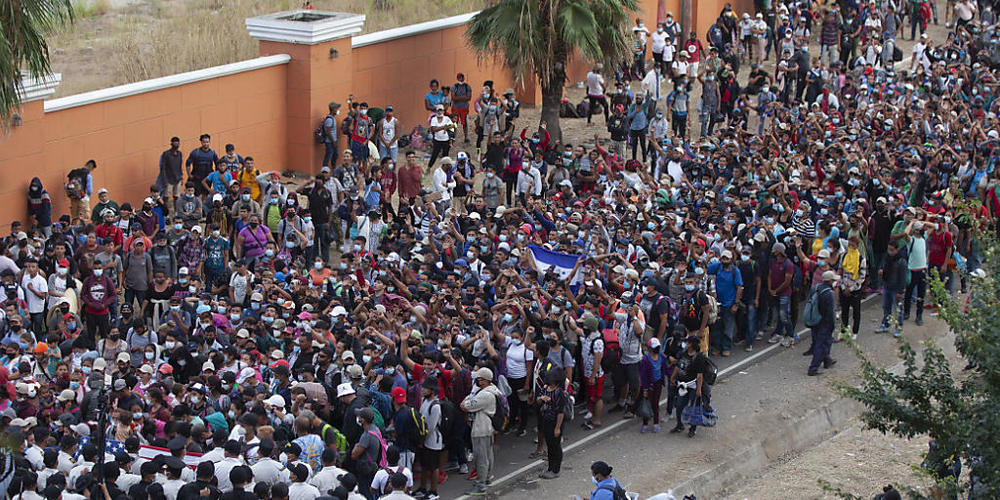 Migranten aus Honduras stehen vor Polizisten, die eine Straße blockieren. Foto: Sandra Sebastian/AP/dpa