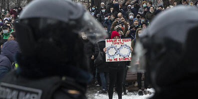 Eine Frau hält gegenüber von Polizisten ein Schild mit Porträts des russischen Präsidentens Putin und der Aufschrift «Wir werden es nicht mehr hinnehmen! Wir haben keine Angst». Foto: Pavel Golovkin/AP/dpa