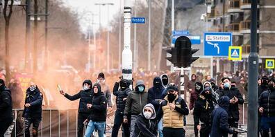 Demonstranten werfen auf einer Straße mit Steinen. Mehrere hundert Menschen haben vor dem Bahnhof von Eindhoven gegen die aktuelle Corona-Politik demonstriert. Foto: Rob Engelaar/ANP/dpa