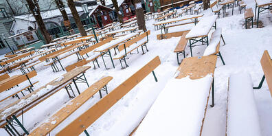 Schnee liegt auf Bierbänken in einem Biergarten im Stadtteil Haidhausen in München. Foto: Peter Kneffel/dpa