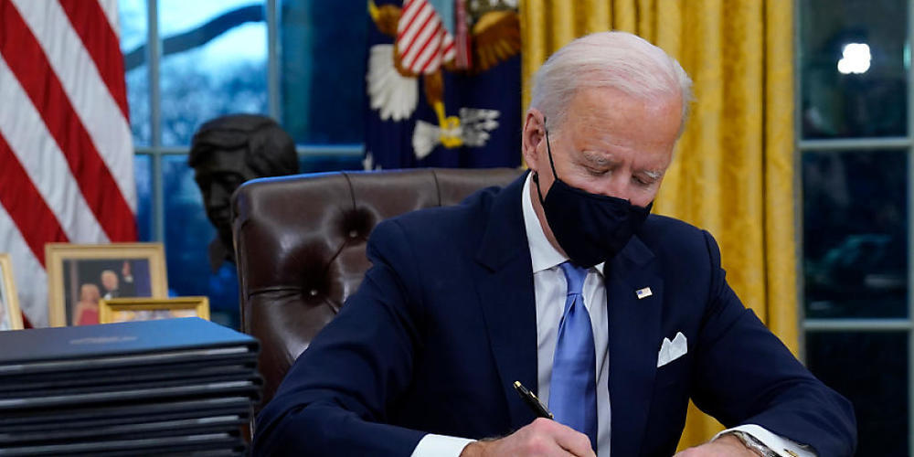 US-Präsident Joe Biden unterzeichnet seine erste Anordnung (Executive Order) im Oval Office des Weißen Hauses. Foto: Evan Vucci/AP/dpa