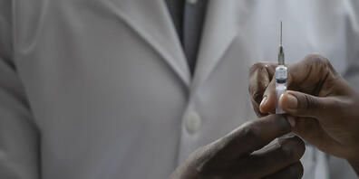 Ein Mitarbeiter des Gesundheitswesens überreicht einem Kollegen eine Spritze mit der Dosis eines Impfstoffs. Foto: Bruna Prado/AP/dpa