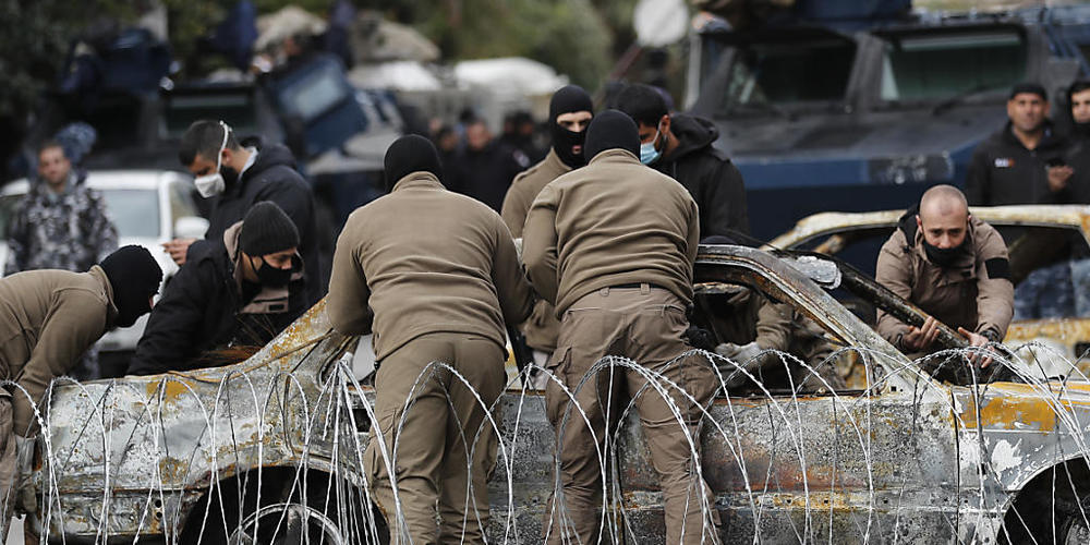 Polizeibeamte entfernen in Tripoli ein Auto, das von Demonstranten während gewaltsamen Auseinandersetzungen mit Sicherheitskräften in Brand gesetzt wurde. Foto: Hussein Malla/AP/dpa