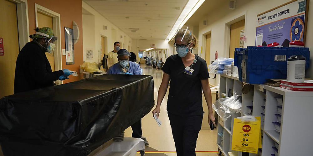 Die Geistliche Kristin Michealsen (r) verlässt eine Corona-Station im Krankenhaus «Providence Holy Cross Medical Center», nachdem sie mit einem Familienmitglied eines verstorbenen Patienten gesprochen hat, während Transporteure eine Trage mit der ...