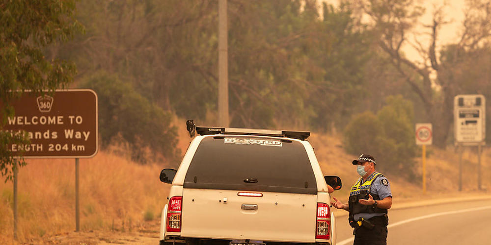 Police talk to residents hoping to return to their properties at a road block on Great Northern Highway in Perth, Tuesday, February 2, 2021. An out-of-control bushfire burning near the Perth Hills has engulfed at least three homes and is threateni...