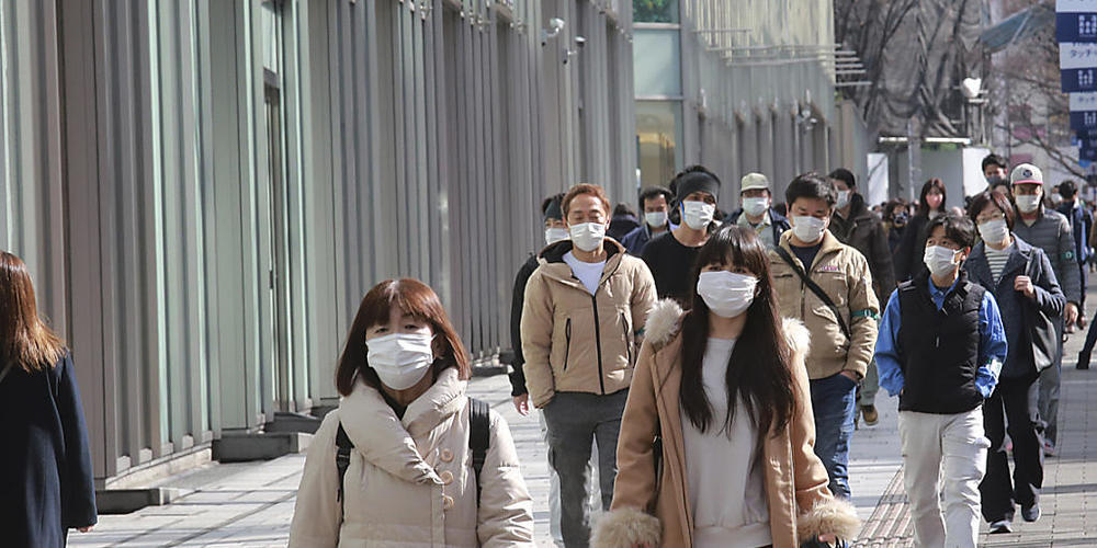 Passanten tragen Schutzmasken und gehen einen Bürgersteig in Tokio entlang. Foto: Koji Sasahara/AP/dpa