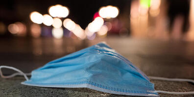 Eine Schutzmaske liegt auf dem Pflaster. Foto: Federico Gambarini/dpa