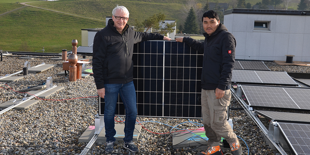 Dieter Baumann, Inhaber Sunconnect GmbH (links) und Latif Qasemi installieren auf einem Flachdach Solarmodule.