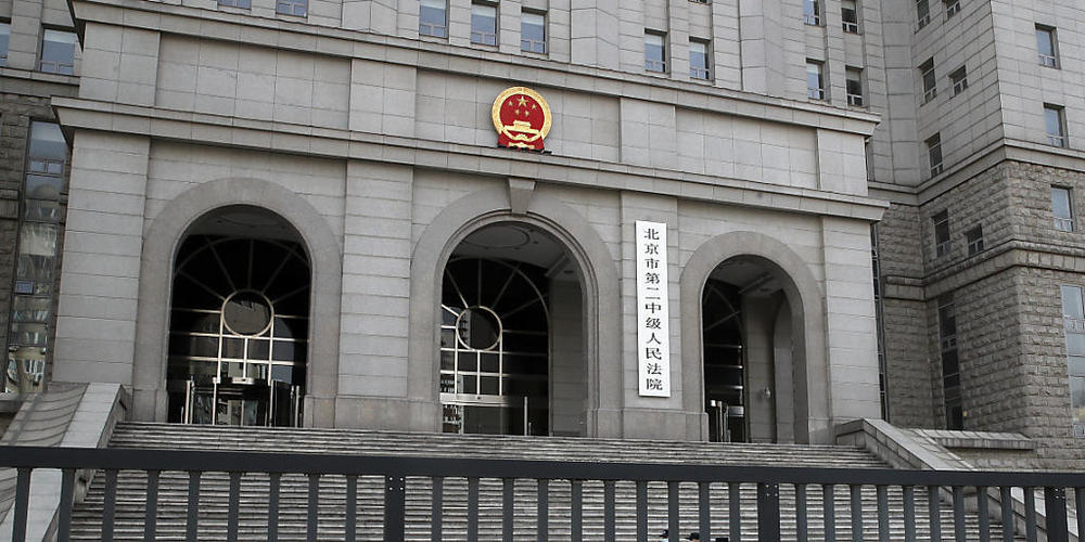 Polizisten mit Mund-Nasen-Schutz patrouillieren auf dem Gelände des «No. 2 Intermediate People's Court». Foto: Andy Wong/AP/dpa