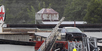 Männer paddeln durch überflutetes Wasser, um überschwemmte Gebäude in Londonderry am westlichen Stadtrand von Sydney zu inspizieren. Foto: Mark Baker/AP/dpa