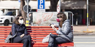 Schutzmasken gehören mittlerweile zum Alltag, so wie hier in Lugano, wo zwei Frauen auf einer Sitzbank verweilen. (Themenbild)