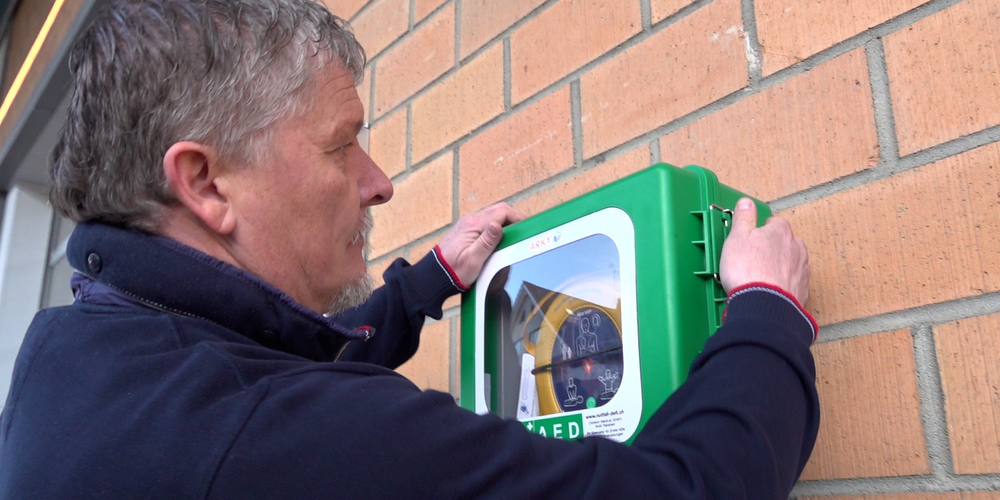Einer der öffentlich zugänglichen Defibrillatoren wird montiert