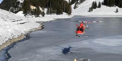 Ein Rega-Notarzt wird an der Rettungswinde ins Eisloch hinunter gelassen, um die beiden im zugefrorenen Seealpsee eingebrochenen Männer nacheinander aus dem eiskalten Wasser zu retten.