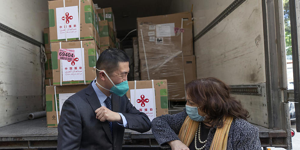Guo Wei, Leiter des Büros der Volksrepublik China bei der Palästinensischen Autonomiebehörde, und Mai Al-Kaileh, Gesundheitsministerin der Palästinensischen Autonomiegebiete, begrüßen sich vor einem Lastwagen mit einer Ladung von Dosen des Corona-...